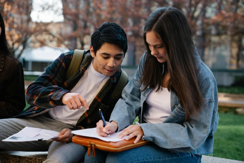 a young man and woman writing on a piece of paper