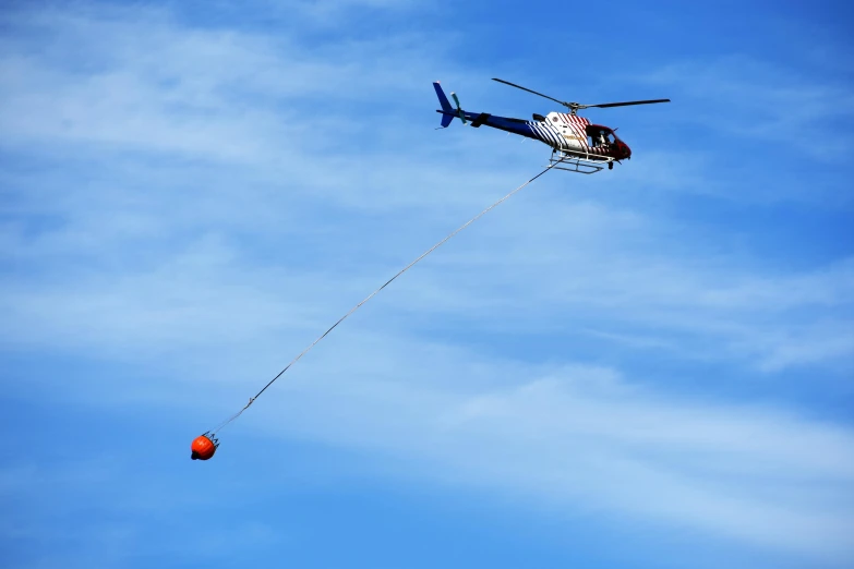 a helicopter has the tip of an object hooked up to a string