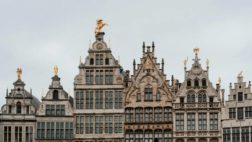 an ornate building that is very tall and has two gold sculptures on the top of it