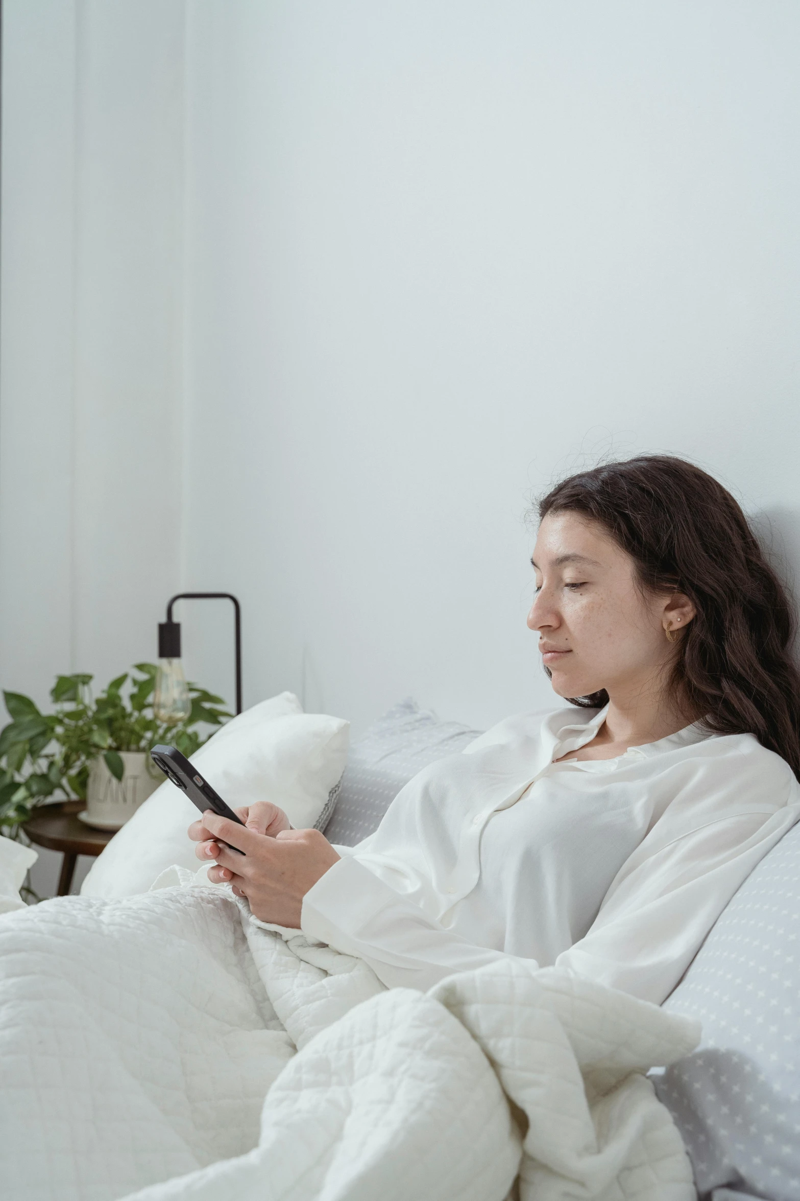 a woman lays on the bed while looking at her phone