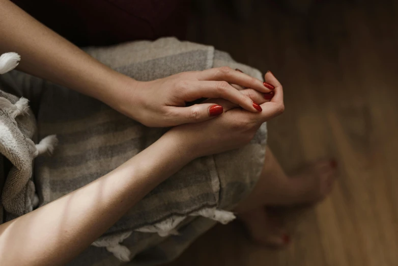 two people who are sitting together on a wooden floor