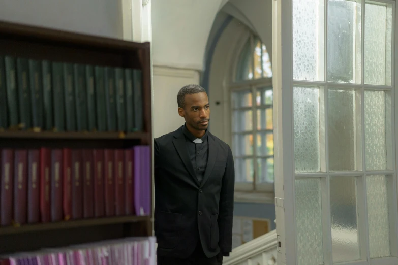 the black man is standing near bookshelf in church