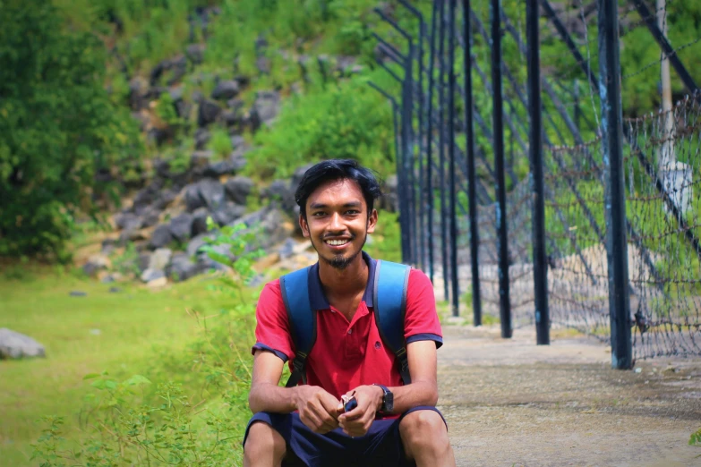 a man in red shirt and blue pants on sidewalk near trees