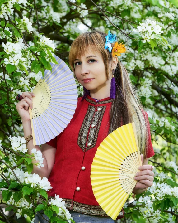 a woman in a red shirt is holding two fan