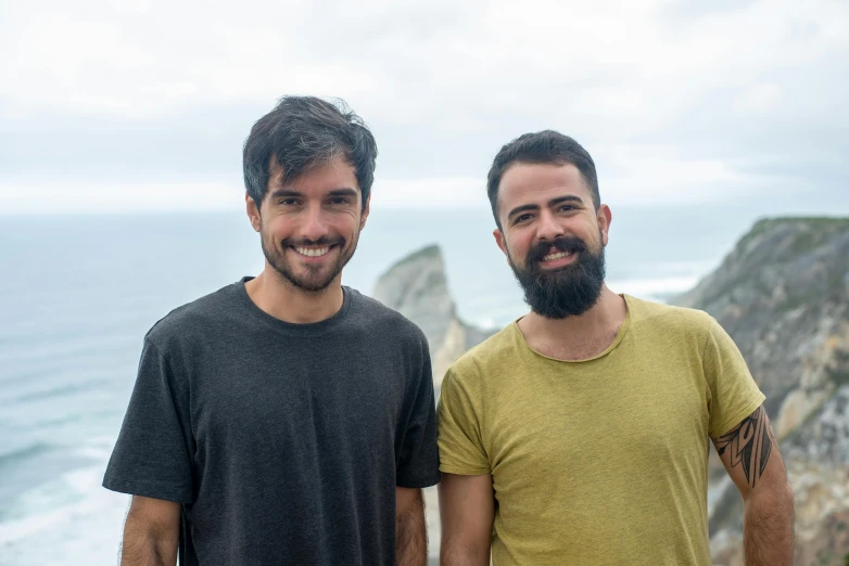 two men standing next to each other at the ocean's edge