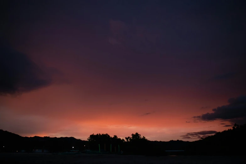 an airplane flies as the sun sets behind a cloud