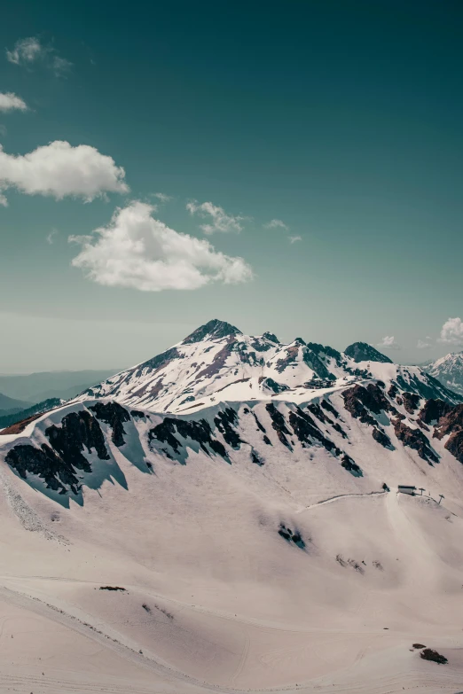 a very tall snow covered mountain side in the distance