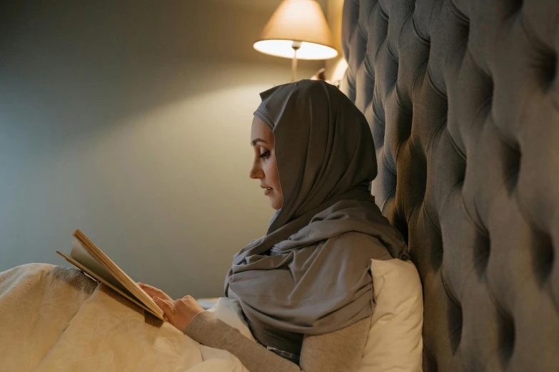 an arabian woman reading a book on her bed