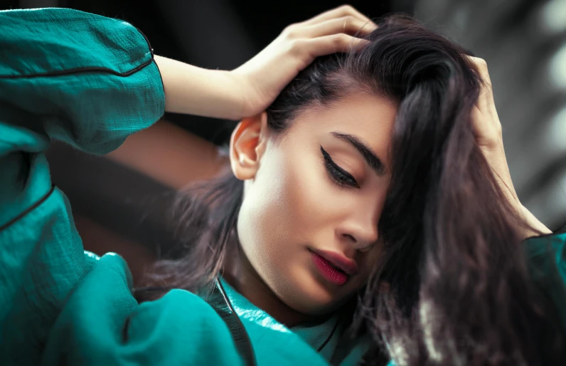 a woman with a green dress is touching her hair