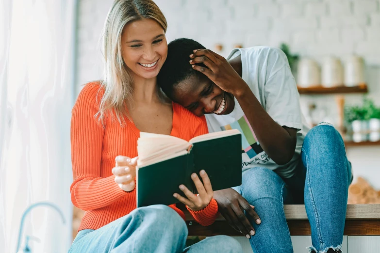 a man and woman sit together on the floor reading a book