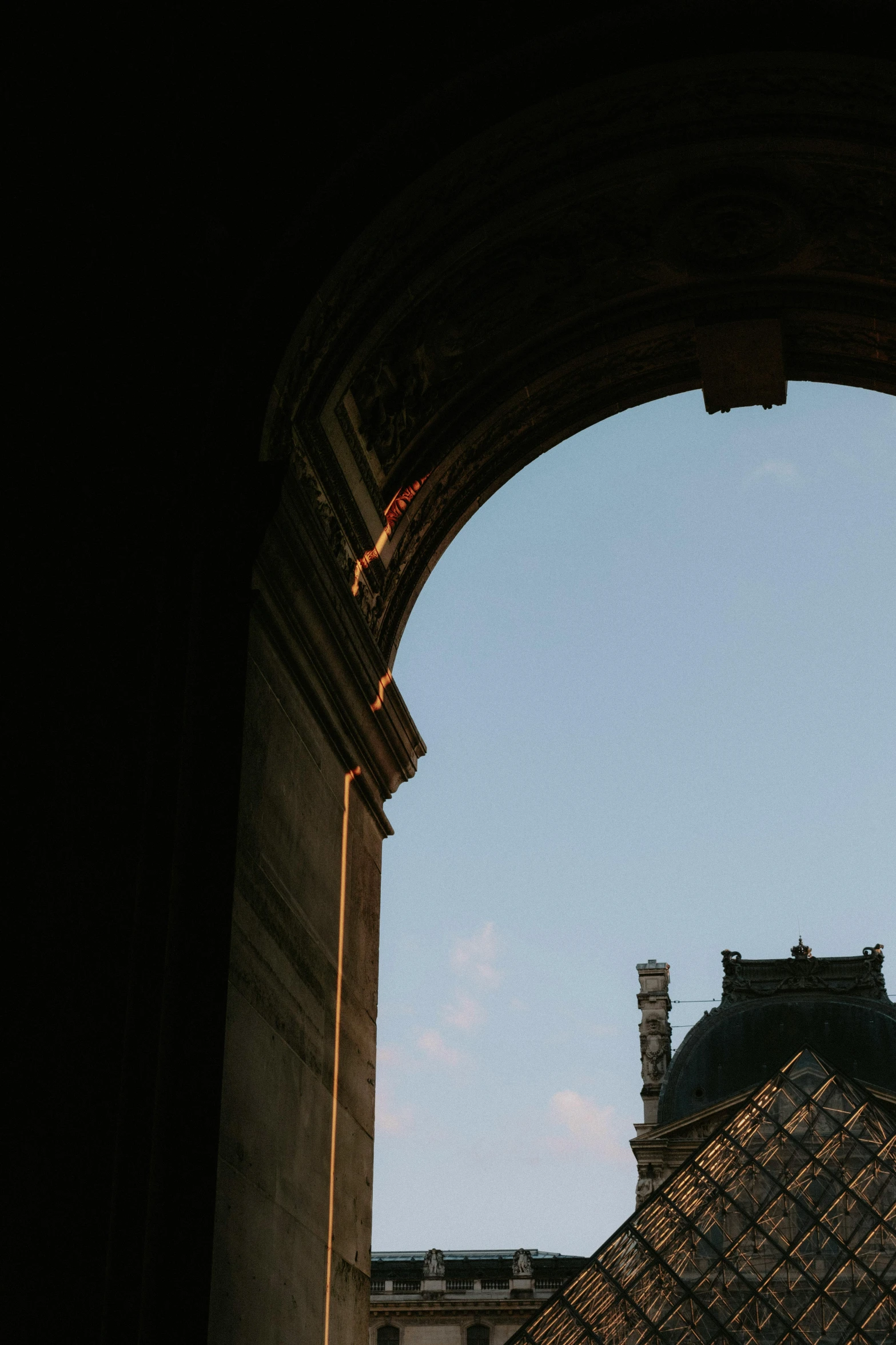 an arch opening to the sky next to two buildings