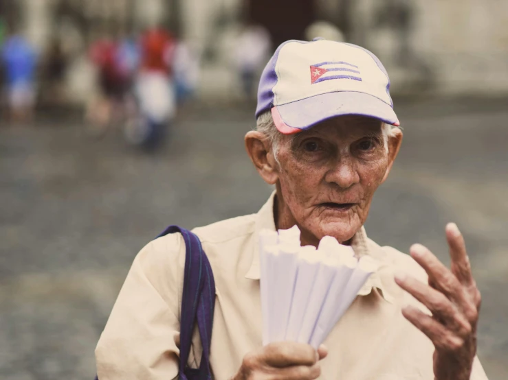 an older man in a baseball cap holds a fan