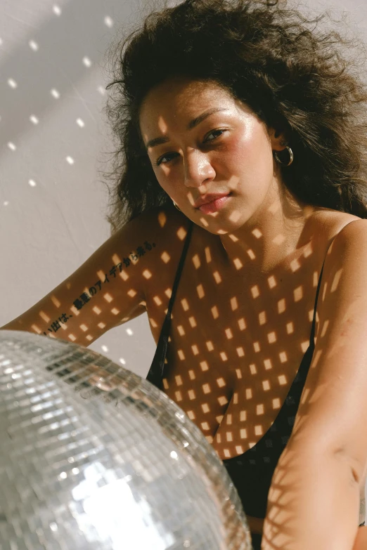 a woman in black top leaning on a disco ball