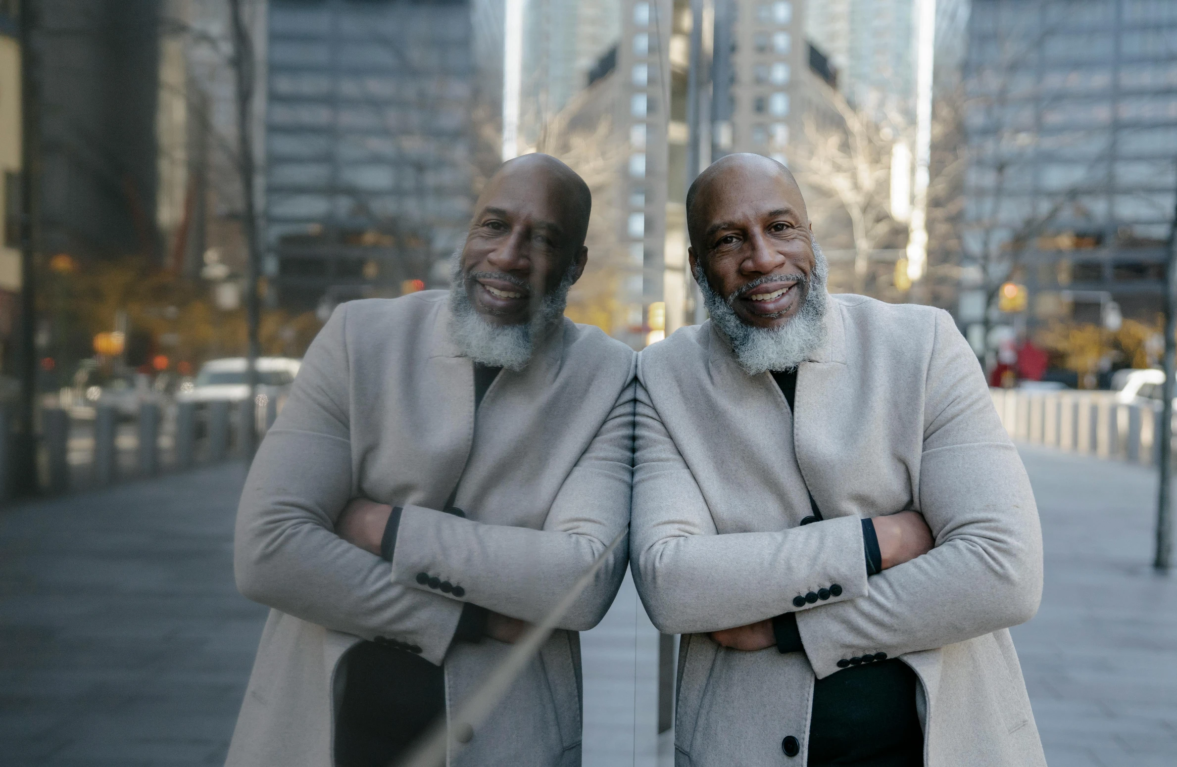 two older men stand together in front of tall buildings