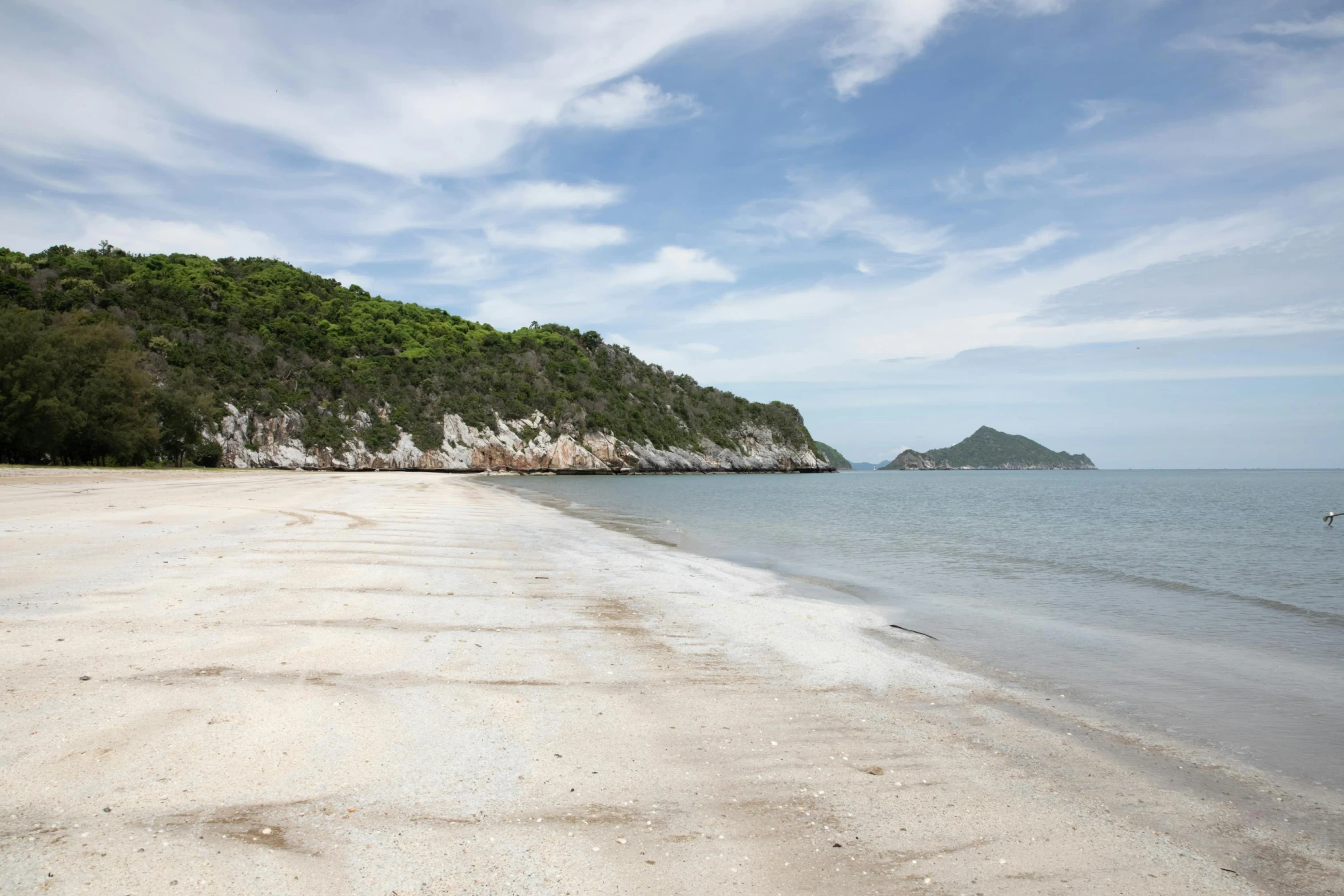 a beach with white sand and a large rock on it's side