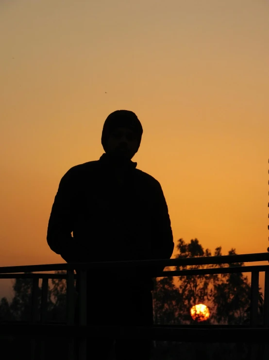 the silhouette of a man on a balcony looking over the city