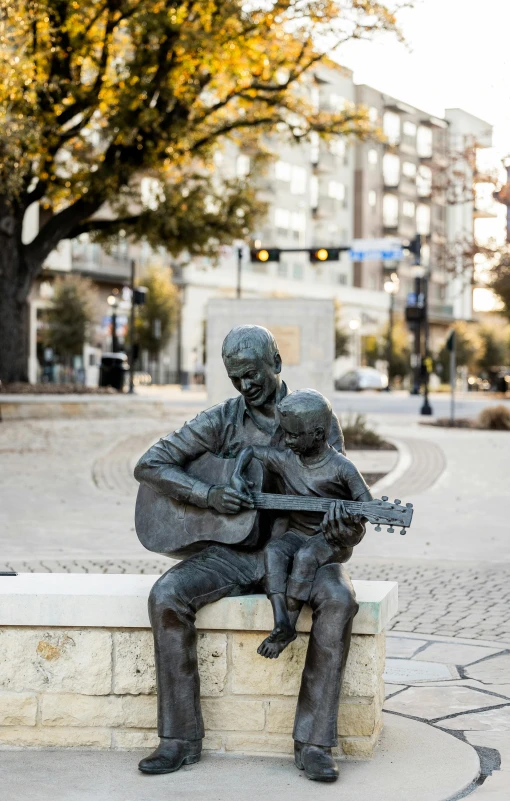 a bronze statue holding a guitar on a wall
