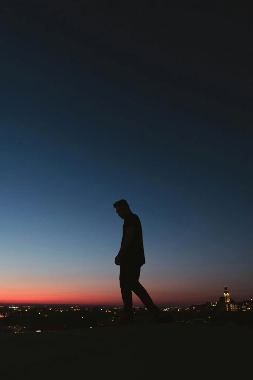 a man with his feet in the air at night with city lights behind him