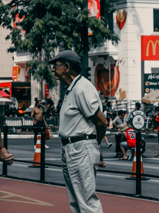 an old man on a cell phone is standing on the sidewalk