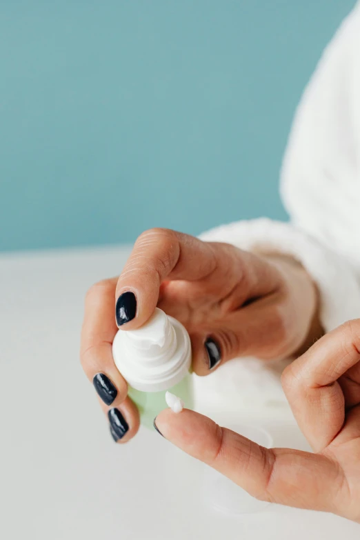 hands are applying a bottle of lotion on a table