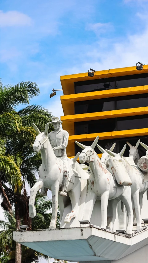 a white statue of some horses riding next to a building