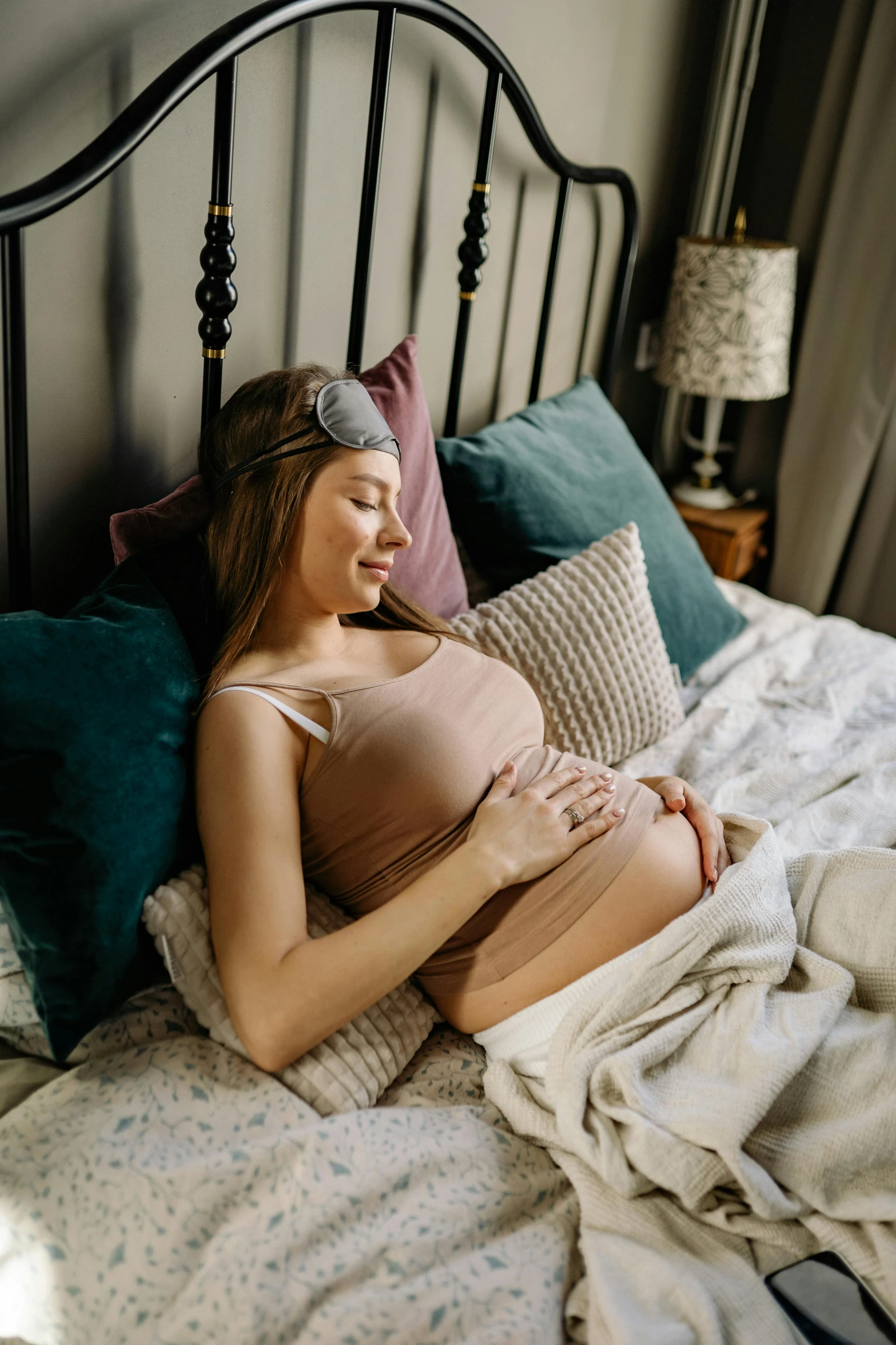 a young pregnant woman laying in bed on her stomach