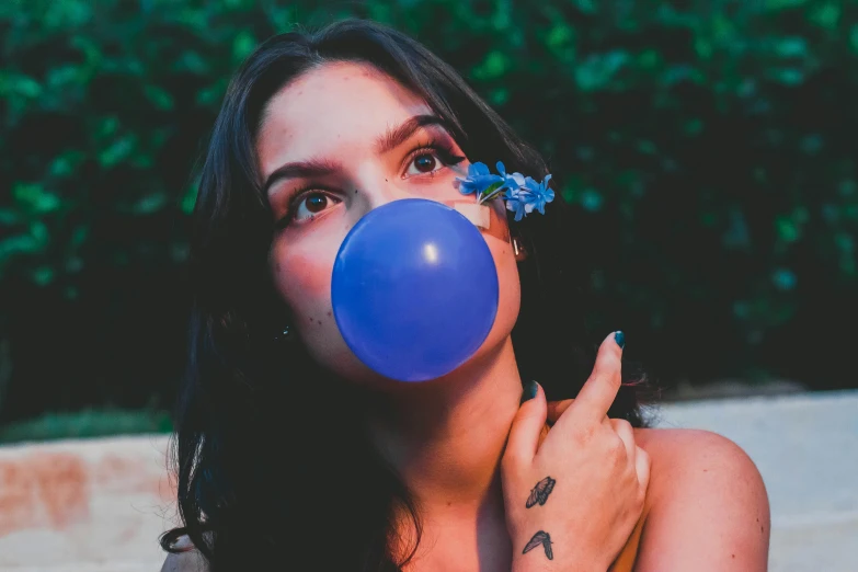 a woman blowing a blue bubble with her finger