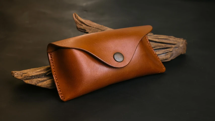 a leather pouch sitting on top of a wooden stick