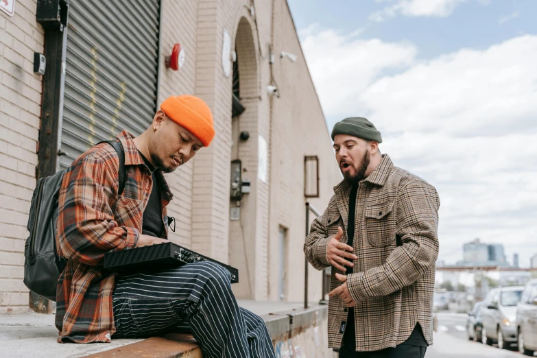 two guys sitting on a curb near a building