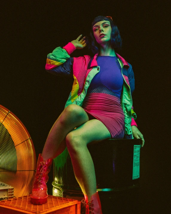 the woman is posing on the desk, with the fan behind her