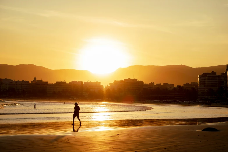 a person walking on the beach during sunset