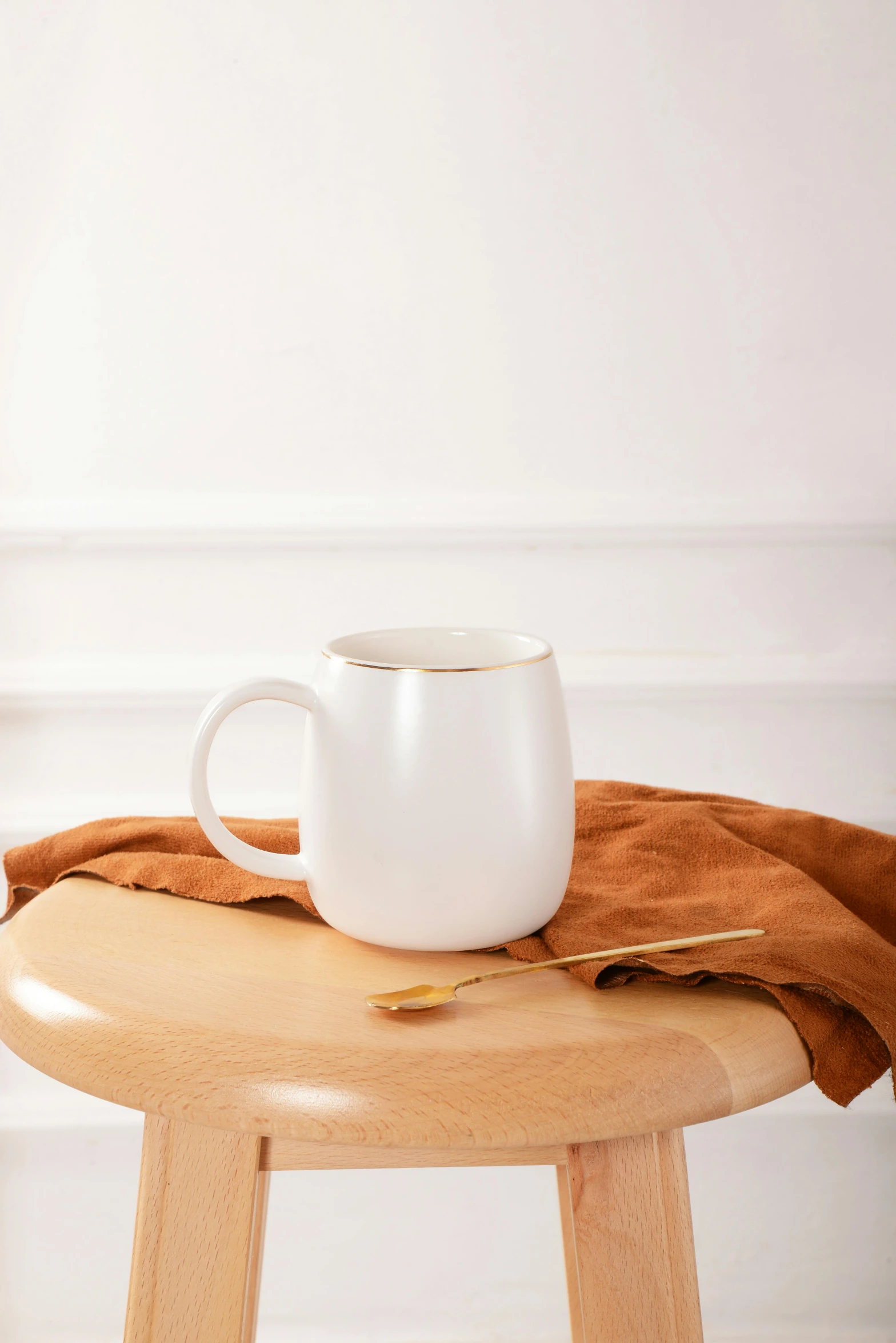 a wooden stool with a white coffee cup and teaspoon