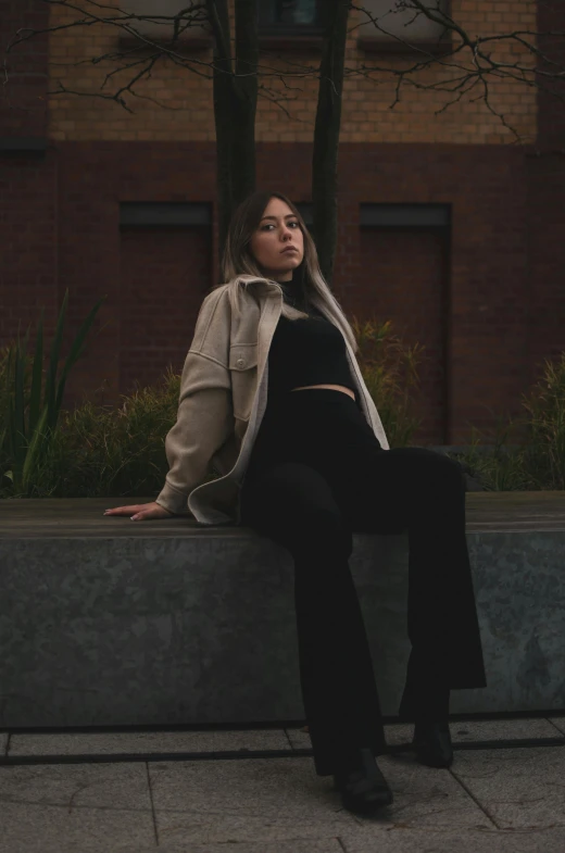 the woman sitting on the ledge is posing for a po