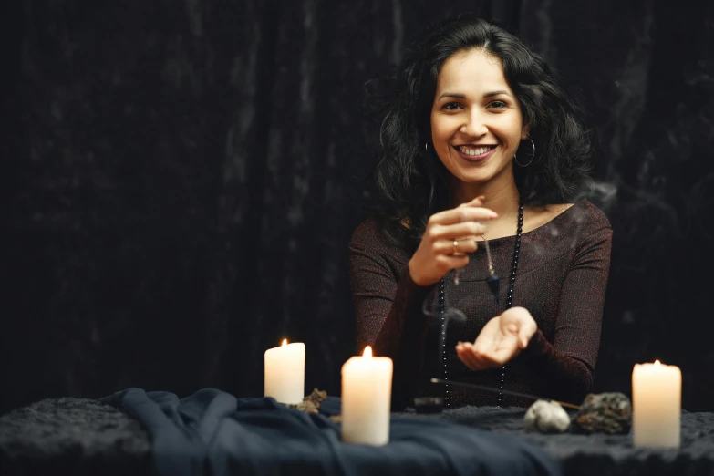 a woman smiling and sitting at a table with candles