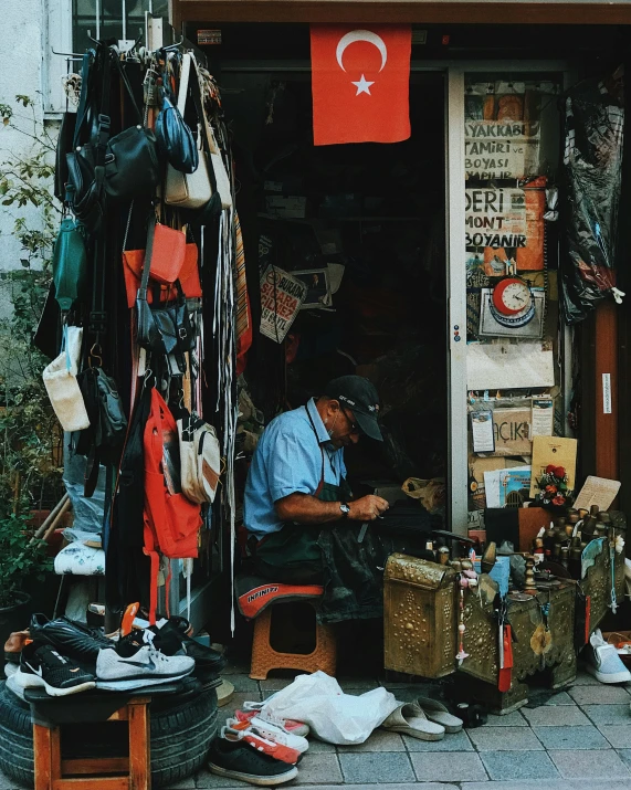a man is sitting on a chair working on luggage in front of a store