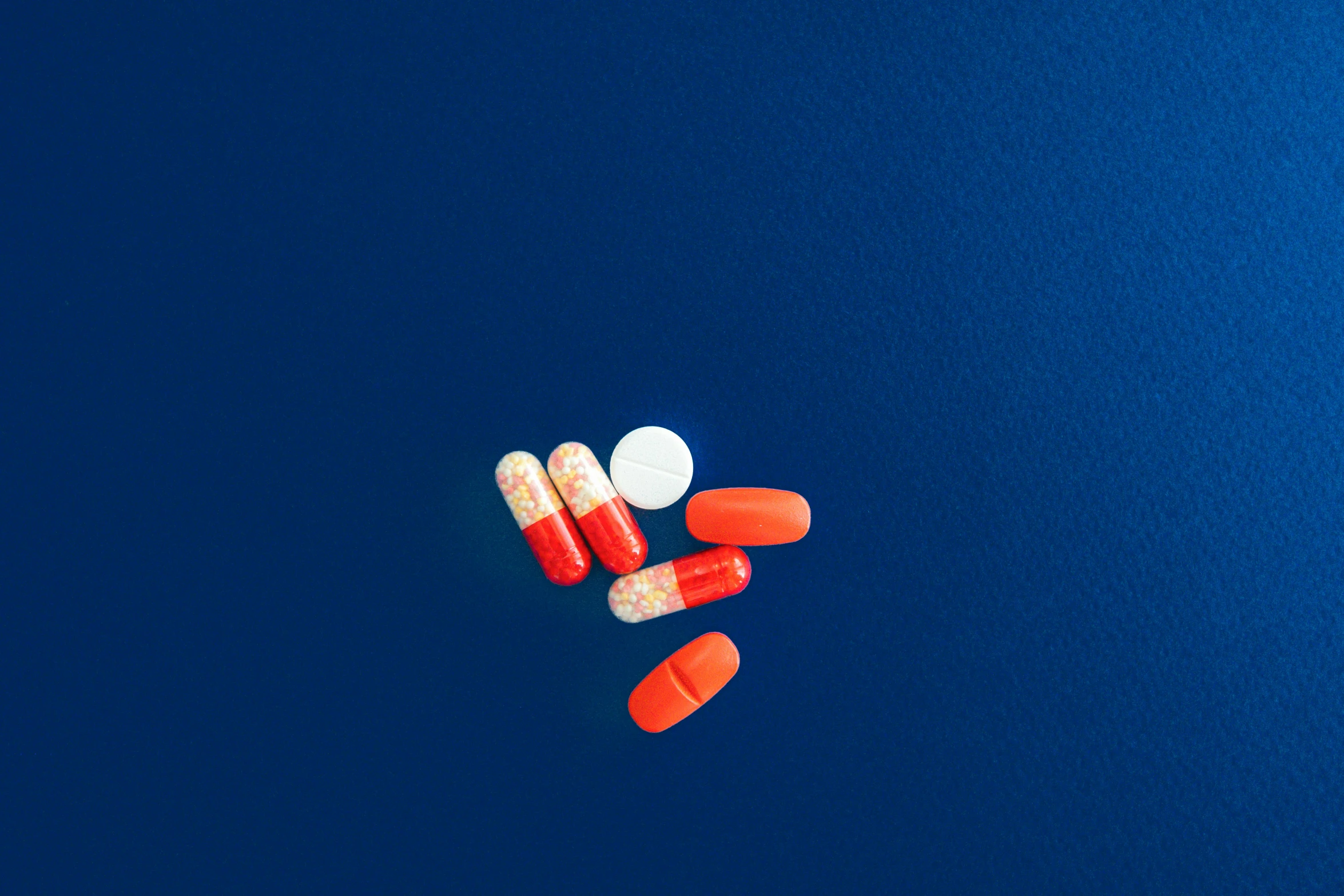 four pills lying on top of a blue surface