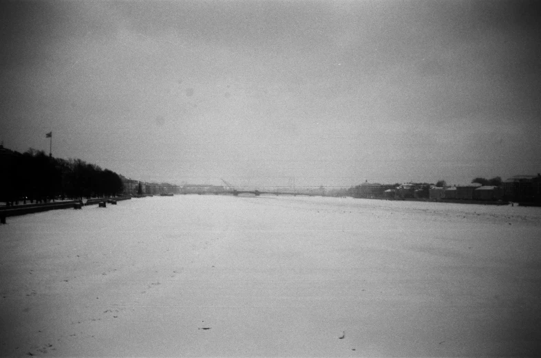 snow covered ground with trees and benches near the water