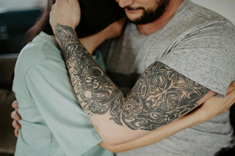 man with a arm tattoo, emcing another mans shoulder