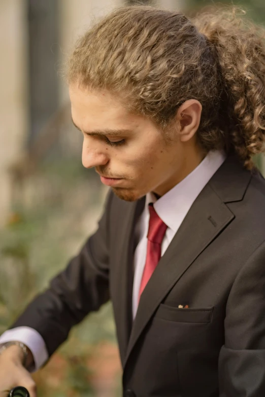 a woman in a suit with a ponytail is holding her cell phone