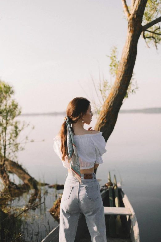 a woman wearing a scarf stands next to the water