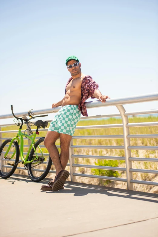 shirtless man leaning on metal fence next to bike