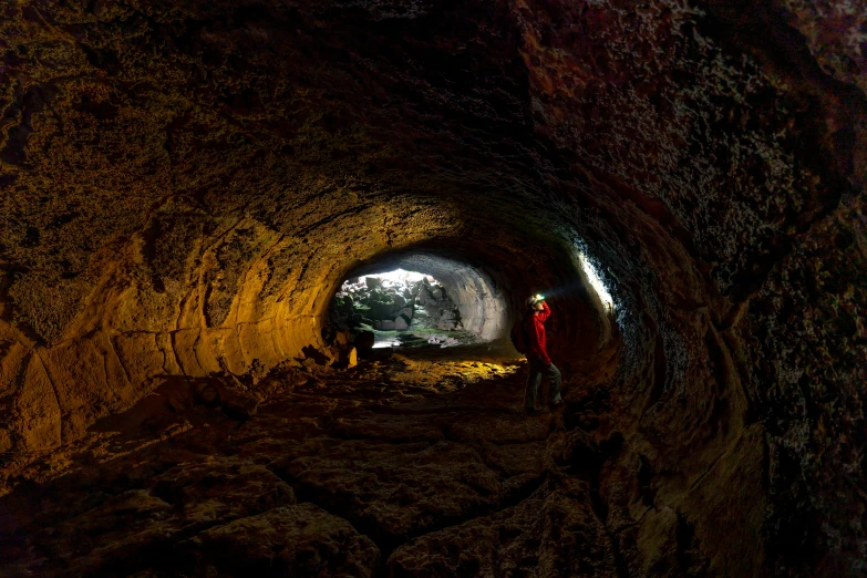 a man stands inside of a stone tunnel