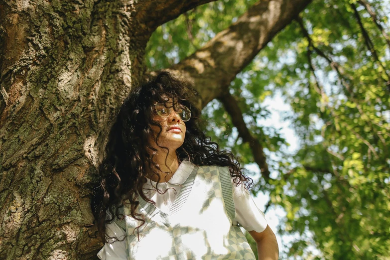 a woman standing against a large tree in the woods