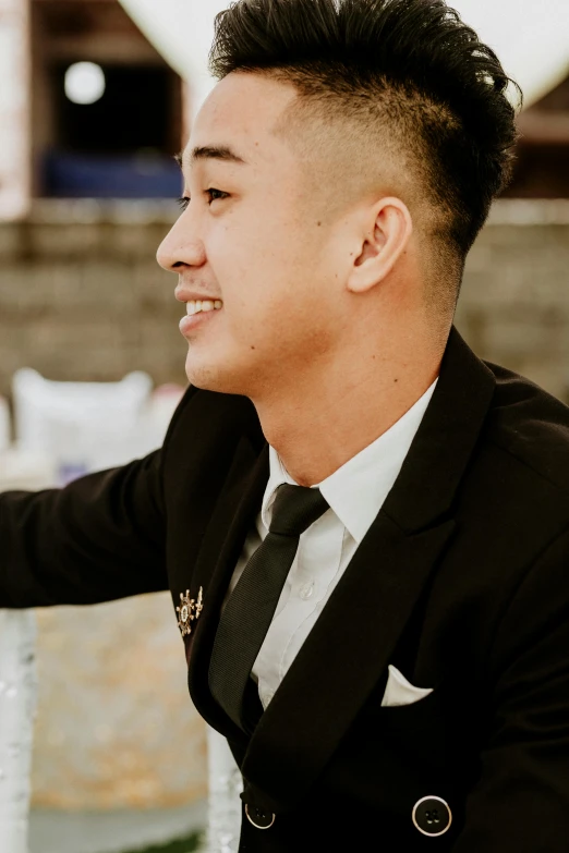 a young man in black suit and white shirt looking at soing