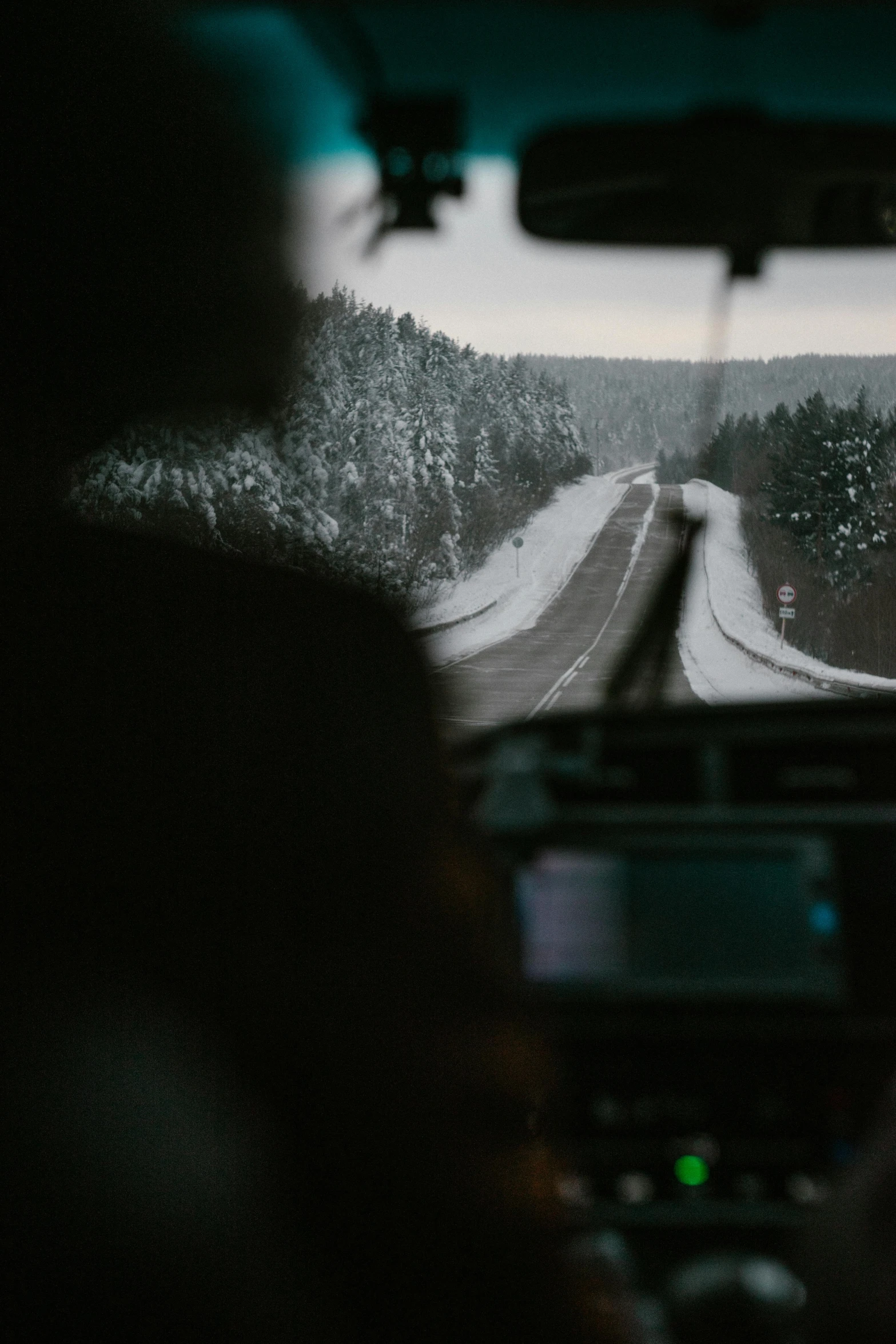 a car is seen from the driver's seat while driving down a snowy road