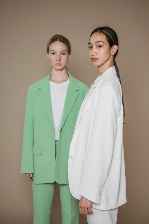 two models stand next to each other in light green clothes