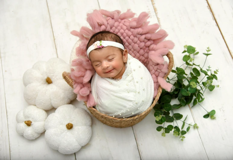 a small baby in a basket sleeps next to two large balls