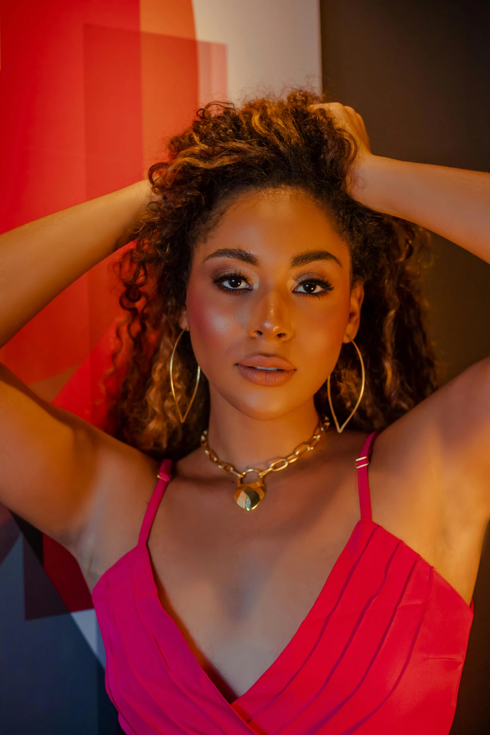 a woman wearing a pink shirt and gold earrings