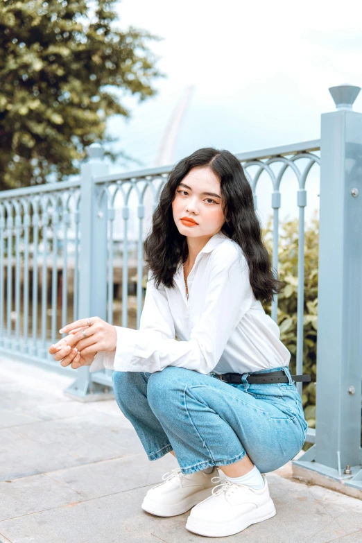 a young woman with dark hair posing on a sidewalk