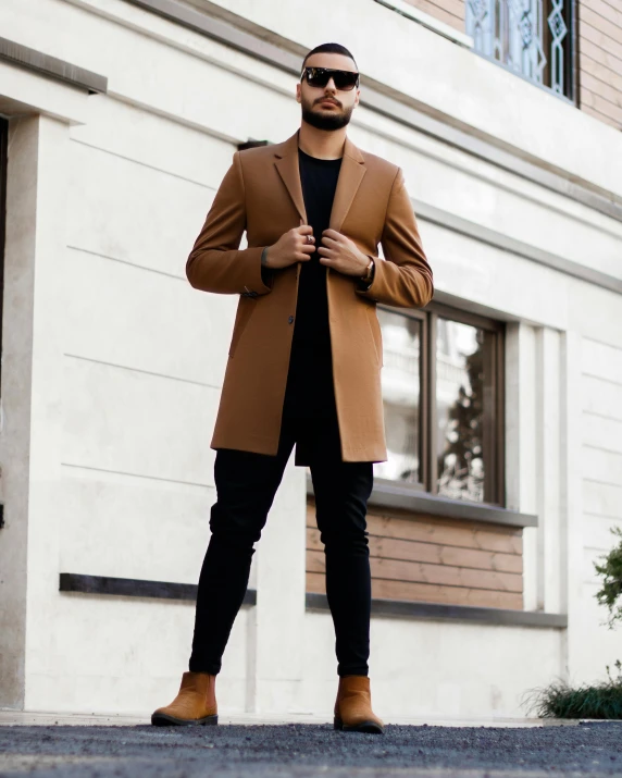 man in brown jacket and boots standing on the street